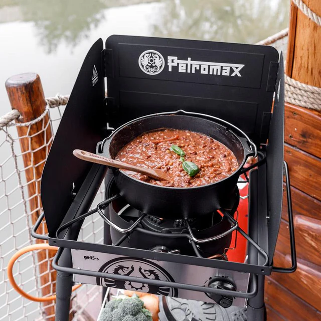 auf einem Gastisch steht ein Chili Con Carne im Dutch Oven, darin steckt ein hölzerner Kochlöffel